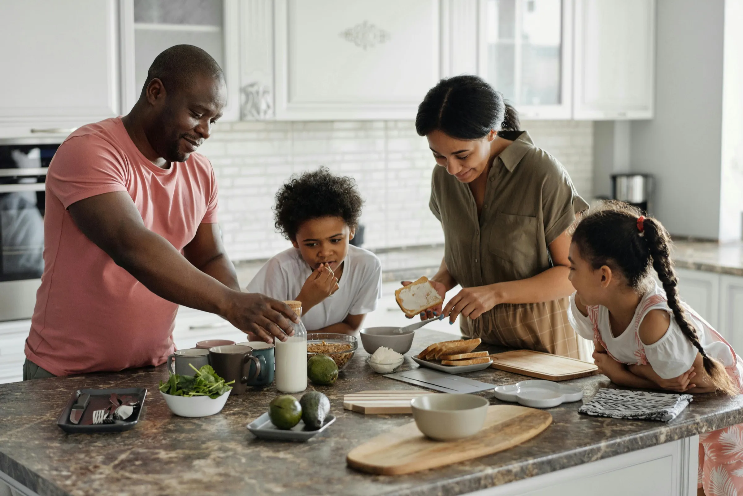 A family of four making breakfast together at their kitchen island